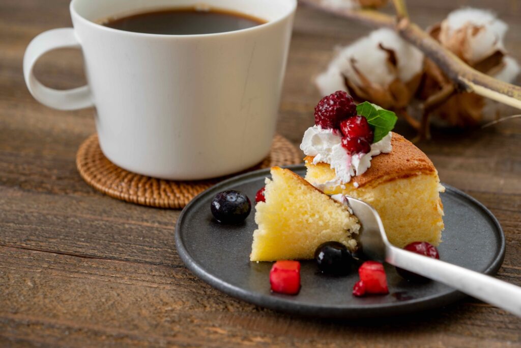 生クリーム、ミント、フルーツで飾り付けされた興部発酵バターケーキとマグカップに入ったコーヒー